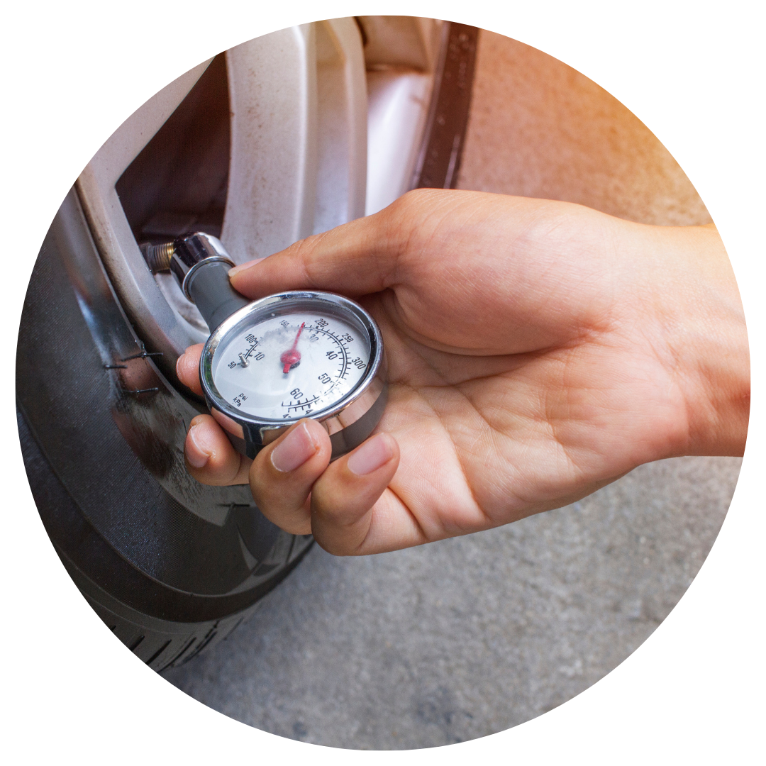 person measuring tire pressure with tire gauge